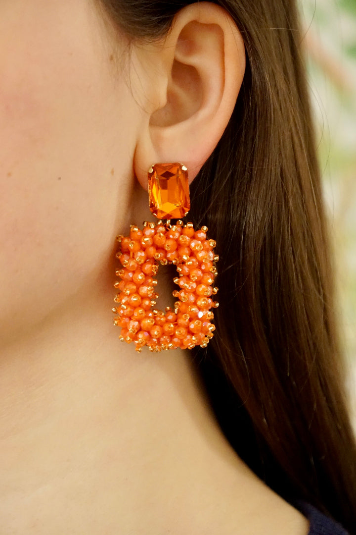 Ohr mit eckigem orangenen Ohrring